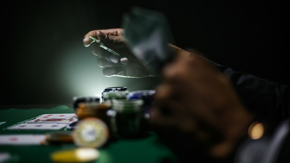 Close-up of hands placing poker chips on a table surrounded by cards and stacks, symbolizing impulsive behavior.