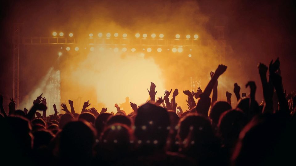 Crowd at a packed concert under bright lights, illustrating potential risk of infections in large gatherings.