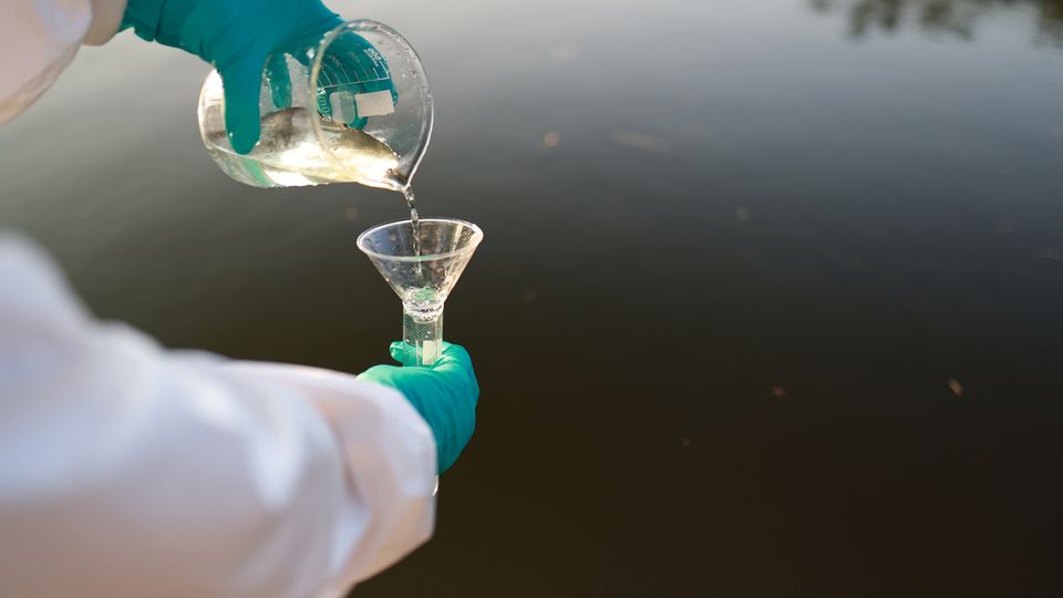 Scientist pouring a water sample for PFAS analysis.