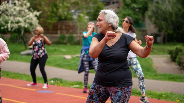 An older woman dances with a group of others. 