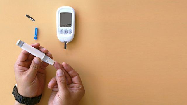 A diabetes patient handling a device for finger prick glucose tests. 