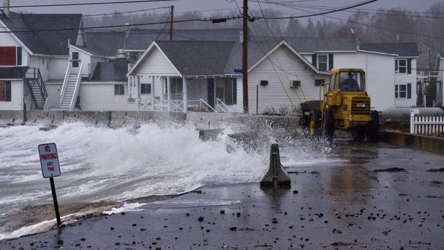 A large wave crashes in front of a house in Maine. 