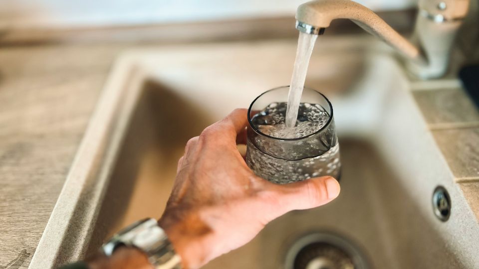 A person filling a glass with tap water.
