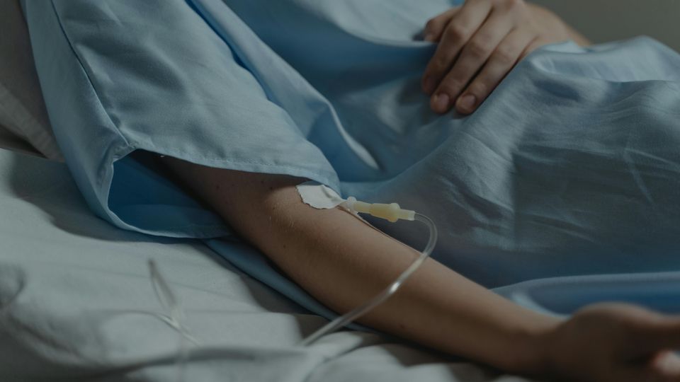 Close-up of a patient's arm receiving treatment in a hospital.