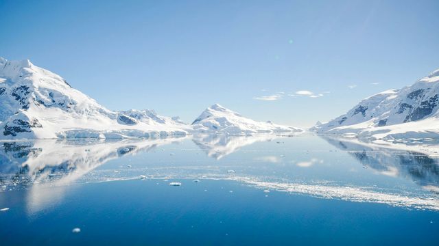 A view of snow-capped mountains across a large frozen lake in Antarctica. 