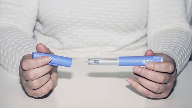 Person holding a GLP-1 injection pen used for diabetes and weight management treatment. 