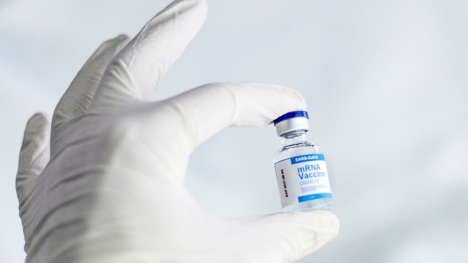 A vial of SARA-Cov2 mRNA vaccine held in a gloved hand
