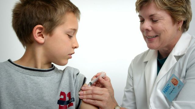 A boy receives a vaccination from a doctor. 