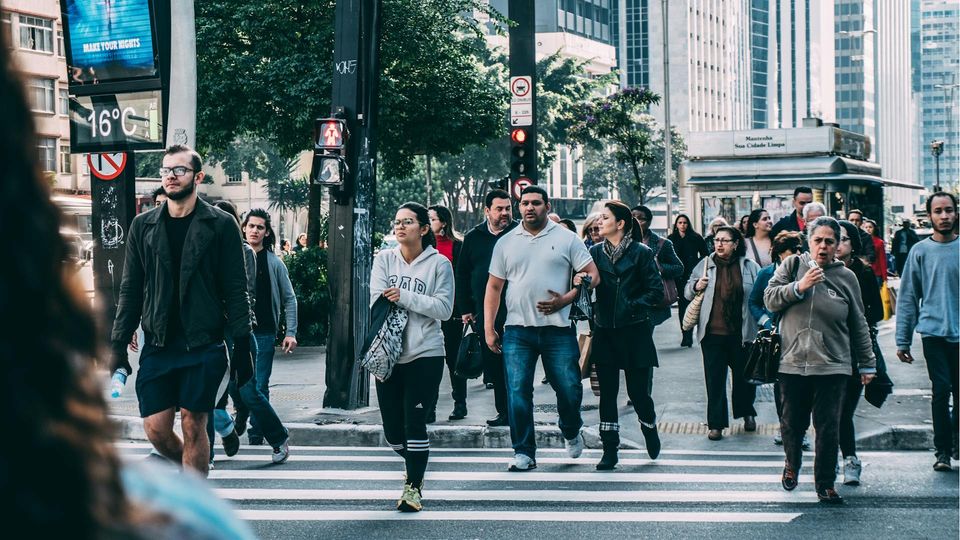 A diverse group of people walking across a city crosswalk, representing variation in population that underpins the principles of personalised medicine.