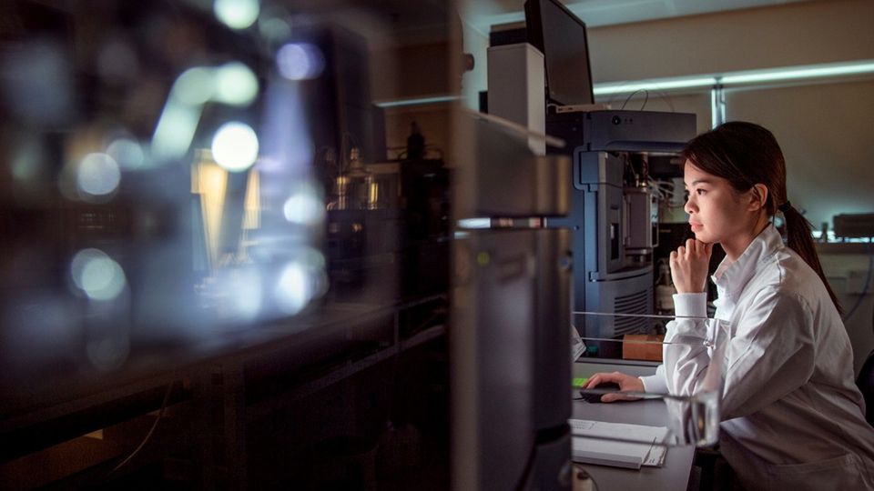 Scientist analyzing laboratory data with AI-driven software on advanced research equipment.