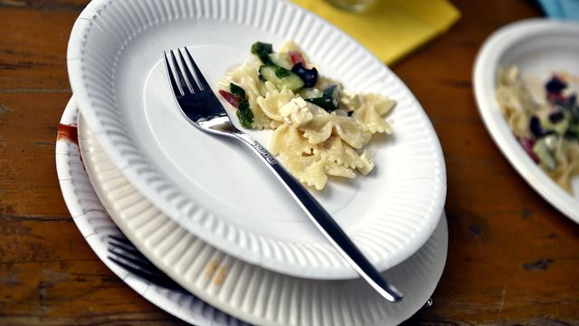 Some pasta and a fork on a white paper plate. 