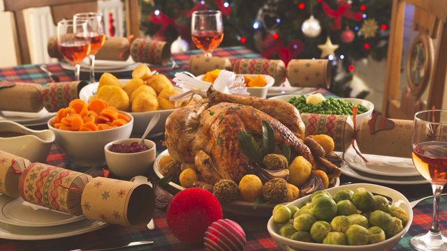 Traditional Christmas dinner table with roast turkey, vegetables and festive decorations. 