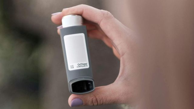 Hand holding an asthma inhaler for quick relief and daily respiratory management. 