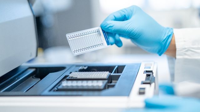 Gloved hand loading microplate with FFPE-derived samples into laboratory analyzer. 