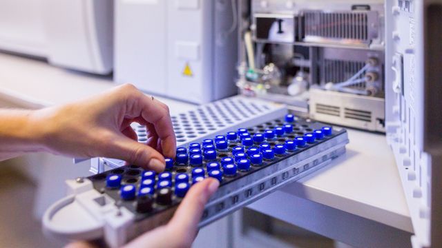 A researcher loading vials of sample into a mass spectrometer. 