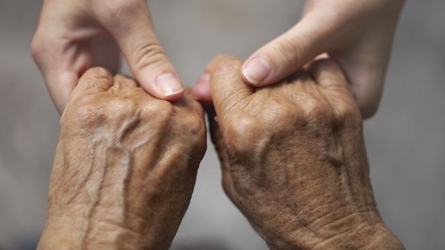 Young female hands, holding older, visibly aged hands.  