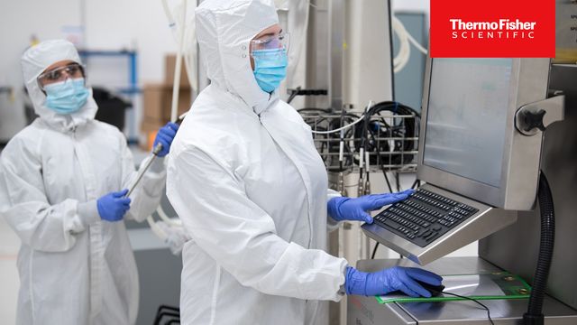 Scientist monitoring stainless steel bioreactor system for protein production in a cleanroom with Thermo Fisher Logo 