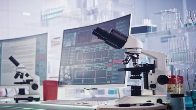 Modern laboratory setup with microscopes and data screens used in protein discovery research. 
