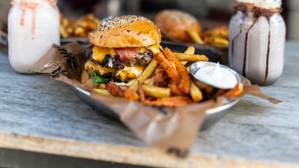 High-fat fast food meal with cheeseburger, fries, and milkshakes, illustrating diet-related blood fat levels.