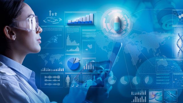 Female scientist wearing safety goggles and holding a tablet. She is surrounded by blue icons representing drug discovery and AI.  