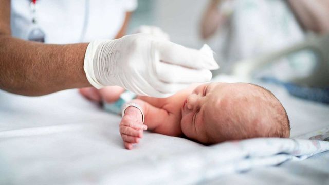 Newborn baby examined by clinician, representing SUDC genetics research and early diagnosis. 