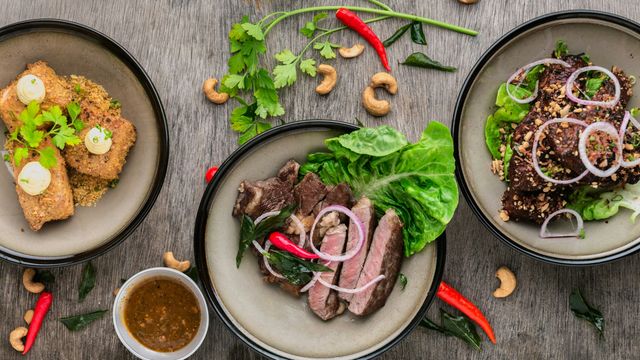 An overhead photograph showing three dinner plates, containing different steak and fried tofu meals. 