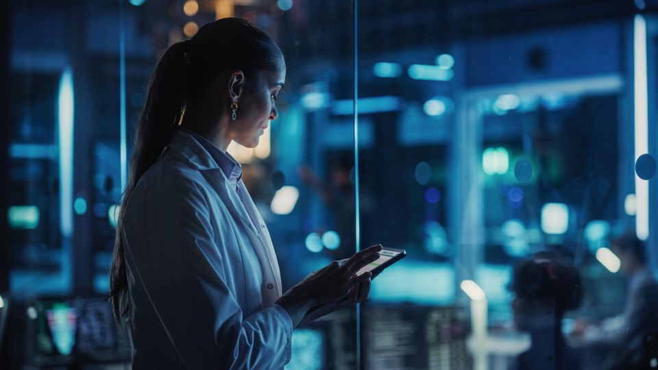 Female scientist holding a tablet inside a laboratory.