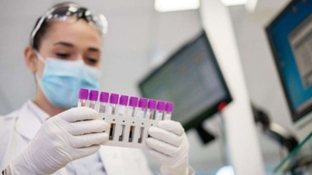 Lab technician handling human tissue samples in test tubes for biomedical research. 