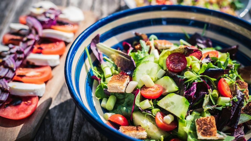 A large blue-and-white striped bowl, filled with a colorful salad.