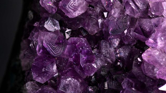 Close-up of purple crystals with geometric patterns and sparkling facets. 