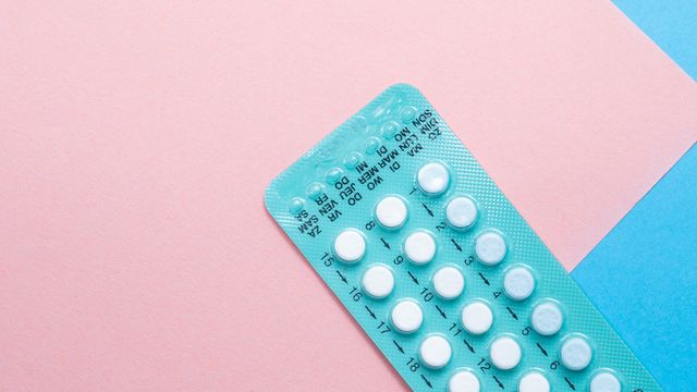 Birds-eye view of blister pack containing white tablets, laid on a pink and blue surface. 
