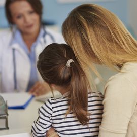 Mother and child consulting with a doctor during a medical appointment, representing rare disease care. 