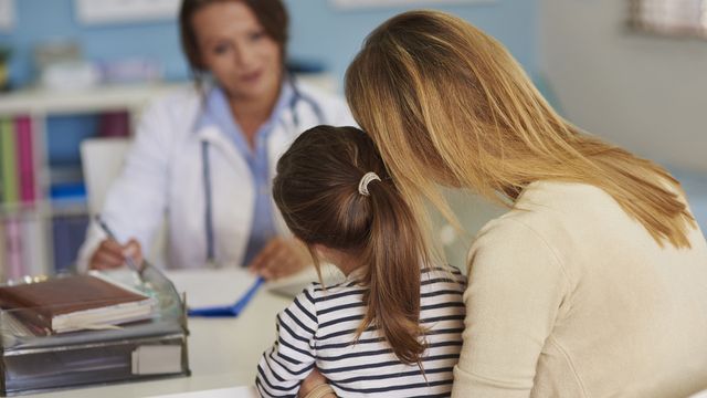Mother and child consulting with a doctor during a medical appointment, representing rare disease care. 