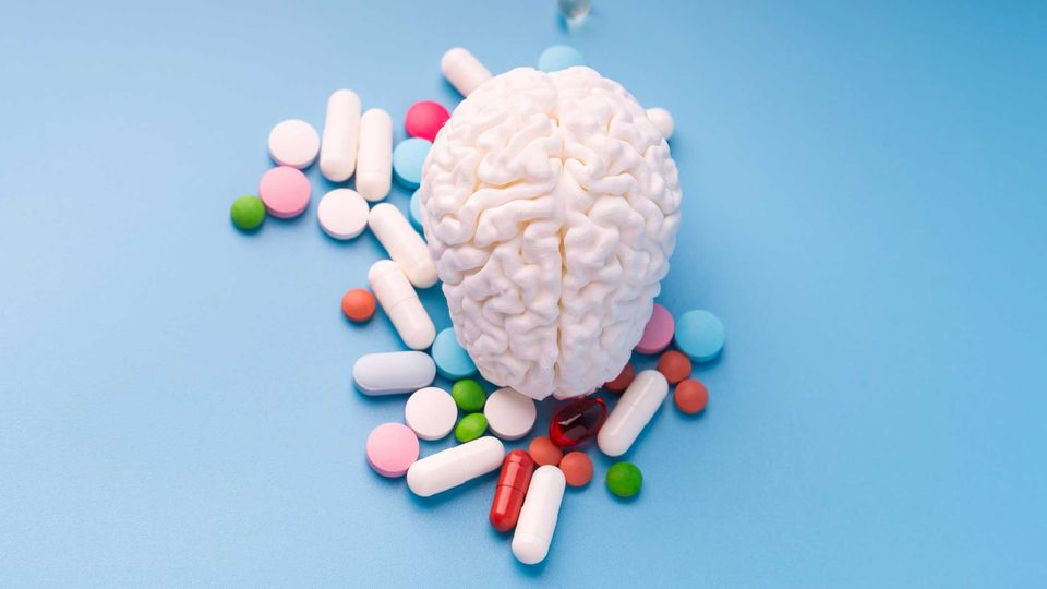 Model of the human brain surrounded by an assortment of medicinal pills.