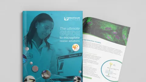 Scientist wearing safety goggles reviewing a guide on microplate reader solutions in a laboratory.