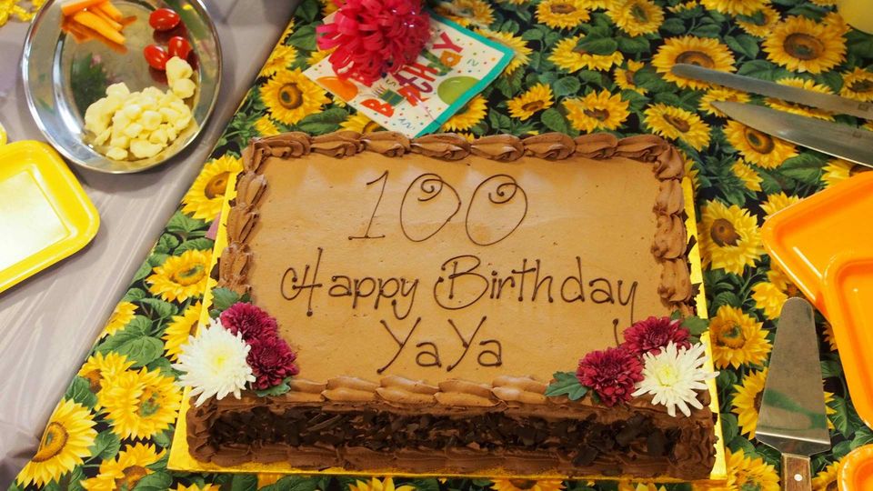 Chocolate birthday cake for a centanarian decorated with flowers and message.