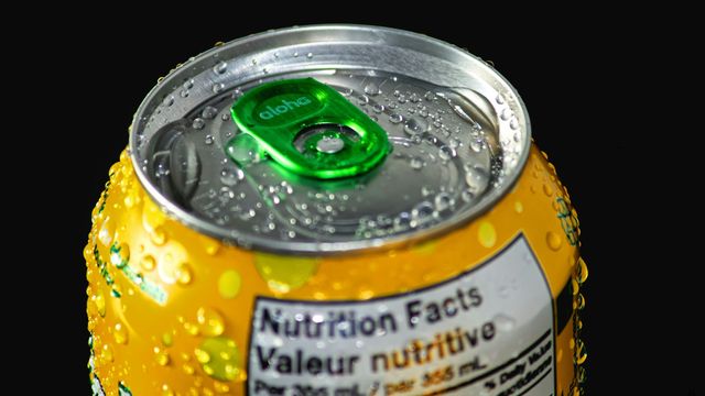 A close-up photograph of the top of a soda can. The can is cold, with condensation droplets on its surface. 