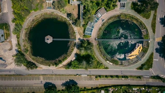 Aerial view of a sewage treatment plant with circular clarifier tanks and filtration basins. 