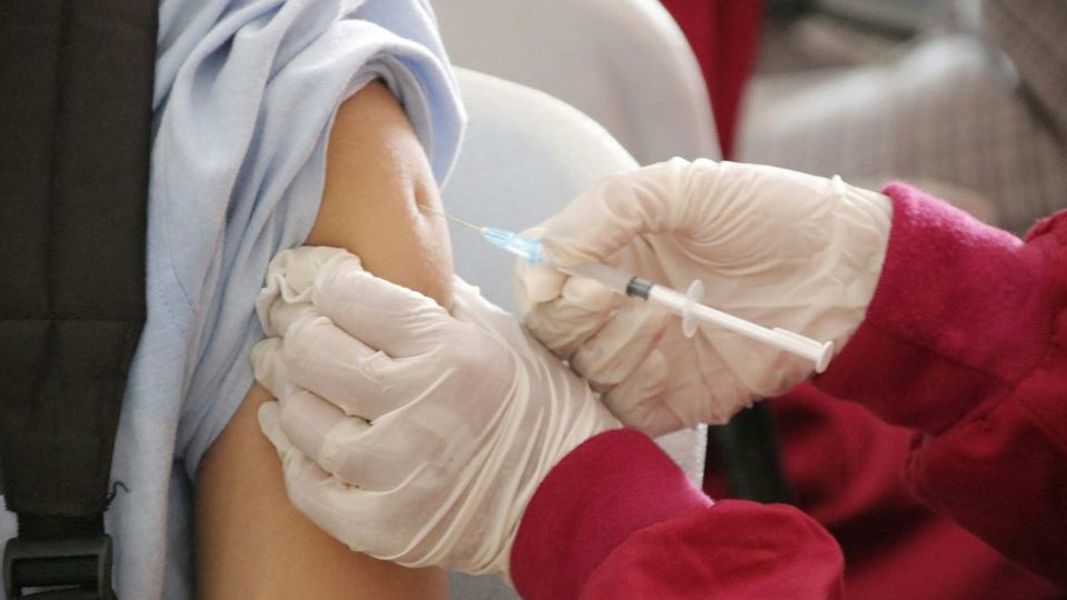 Close-up of a healthcare worker administering a vaccine injection into a patient’s upper arm.