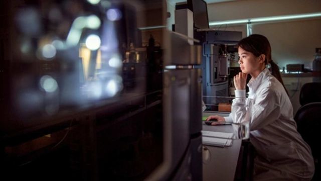 Researcher analyzing data on a computer in a modern laboratory setting. 