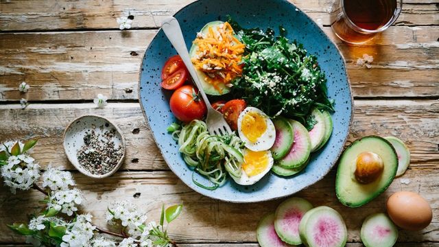 A bowl of salad, with eggs, avocado, tomatoes, and greens. 