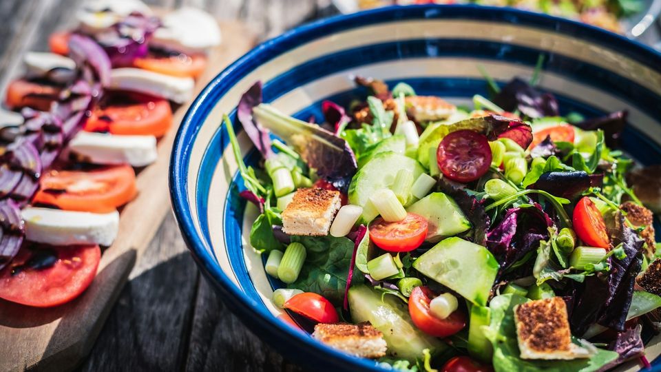 Fresh vegetable salad bowl with tomatoes, cucumber, greens, and croutons.