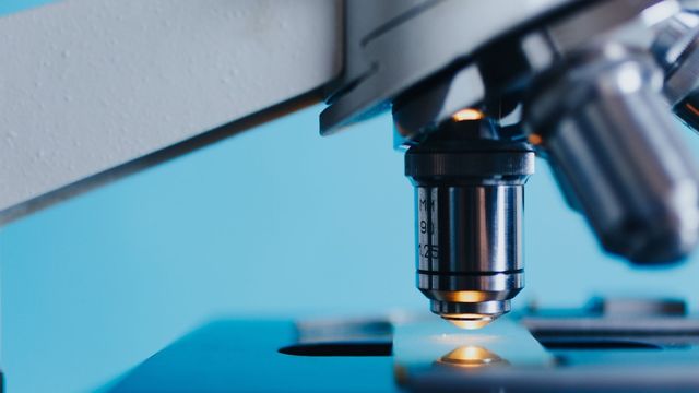 Microscope objective lens focusing on a glass slide for laboratory analysis. 