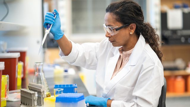 A Black female scientist using a pipette in a lab. 