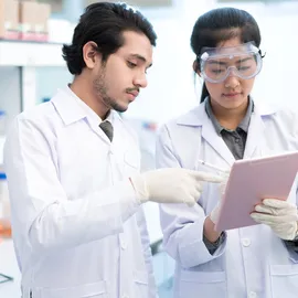 Lab scientists review tablet for drug discovery decisions with unified bio and chemical data.