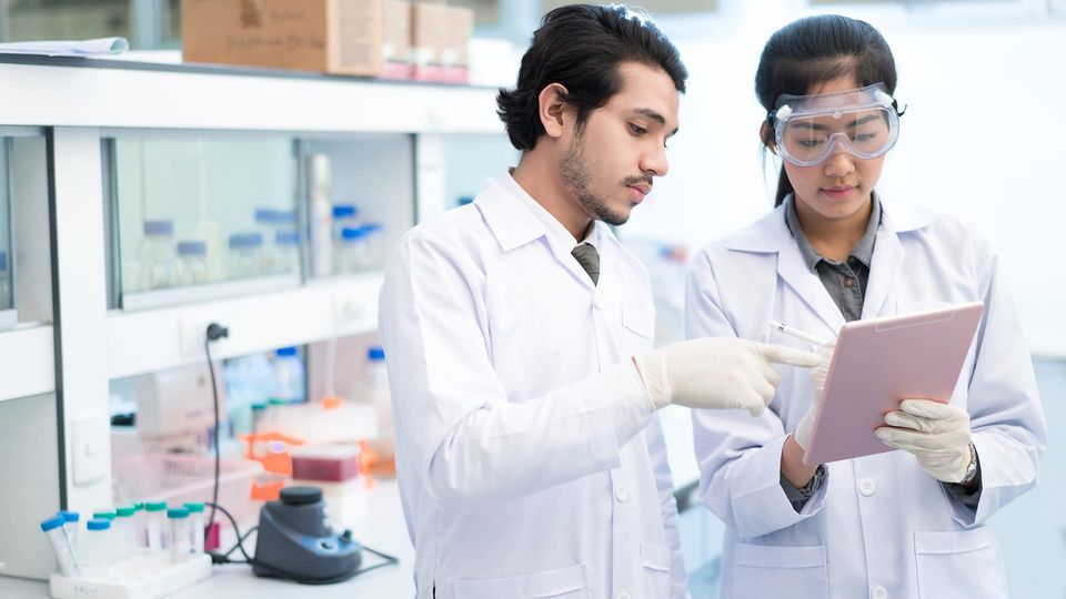 Lab scientists review tablet for drug discovery decisions with unified bio and chemical data.
