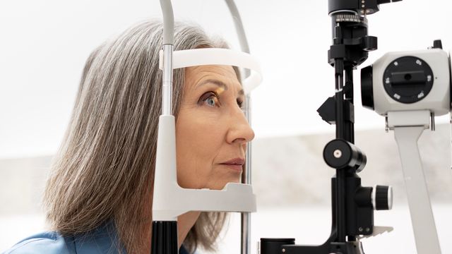 A woman rests her head in a frame as her eye is scanned. 