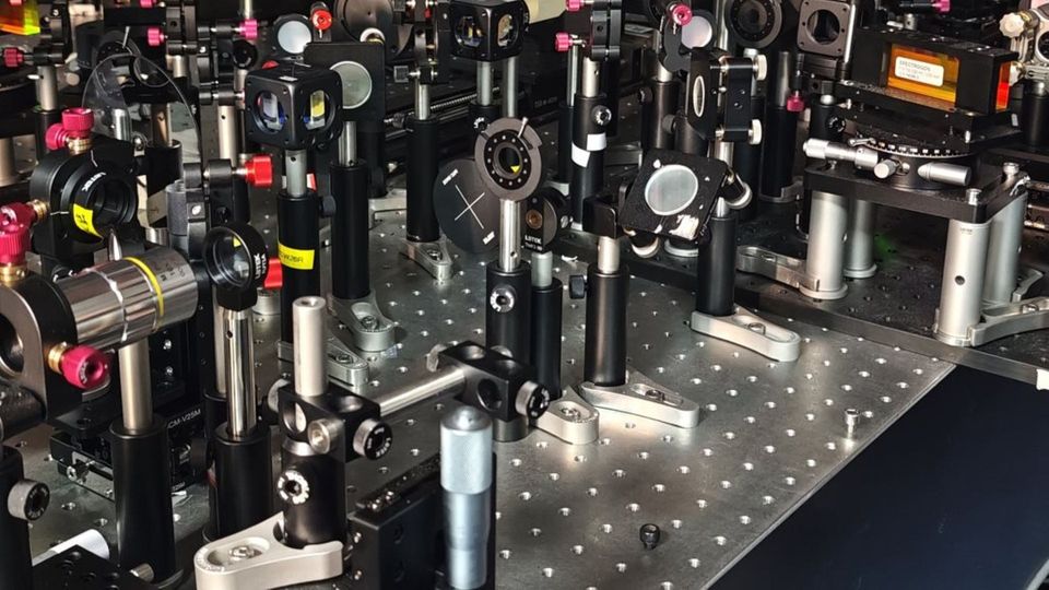 Optical laboratory setup with precision instruments used for compressed spectral–temporal analysis.