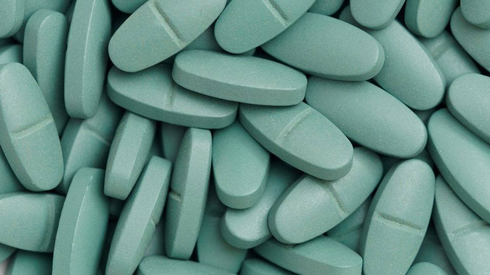 Close-up, birds-eye-view image of multiple oval, green pills.