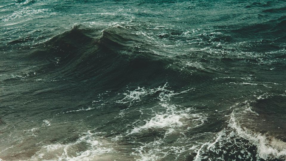Green waves rolling across a choppy ocean with white foam.